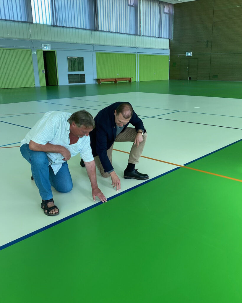 Ortsvorsteher Roland Weber und Oberbürgermeister Ulli Meyer begutachten die neuen Markierungen auf dem frisch sanierten Hallenboden (Bild: F.Jung).