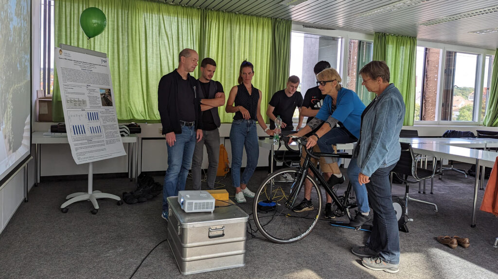Ursula Hubertus von der Ortsgruppe des ADFC testet unter Anleitung Prof. Dr. Stefan Panzer (li.) und seiner Mitarbeiterin Christina Pfeifer (3.v. li.) den Versuchsaufbau zur Gefahrenerkennung auf dem Fahrrad.